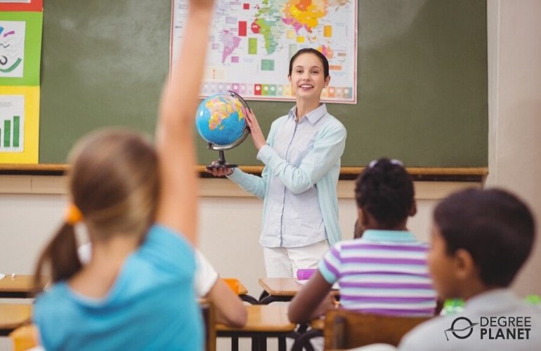 elementary school teacher holding a globe while teaching